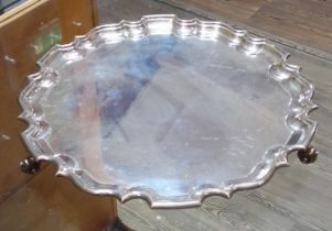 A late Victorian/Edwardian large silver salver, scalloped edge, stood on three scroll feet,