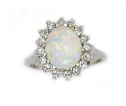 An opal and diamond cluster ring, the oval opal cabochon measuring approximately 12.58mm x 9.93mm,