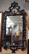 A French style wall mirror, ebonised carved wood frame, 124cm x 59cm (overall).