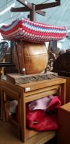 A red cow hide rug, a vintage stool, vintage solid wood table, a leather pouffe and a teak nest of
