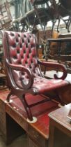 An Ox- blood red leather Chesterfield slipper chair