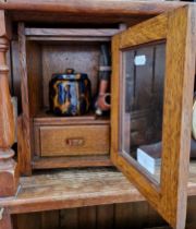 A smokers cabinet with tobacco jar, three pipes and a cutter/pricker.