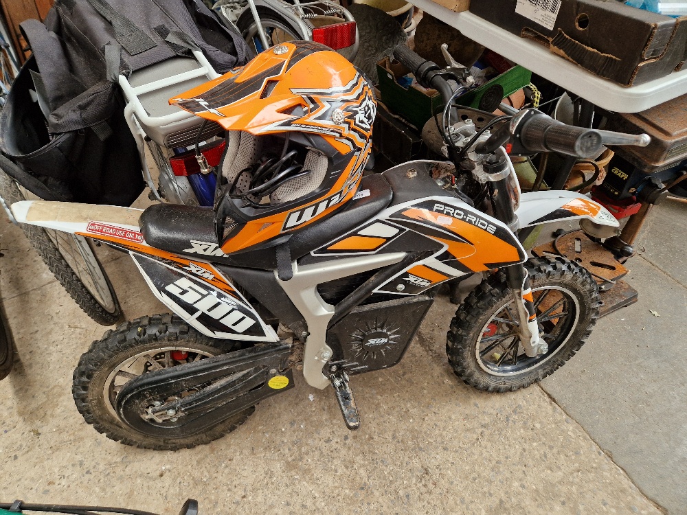 An electric mini motorbike (as found) with helmet and charger.