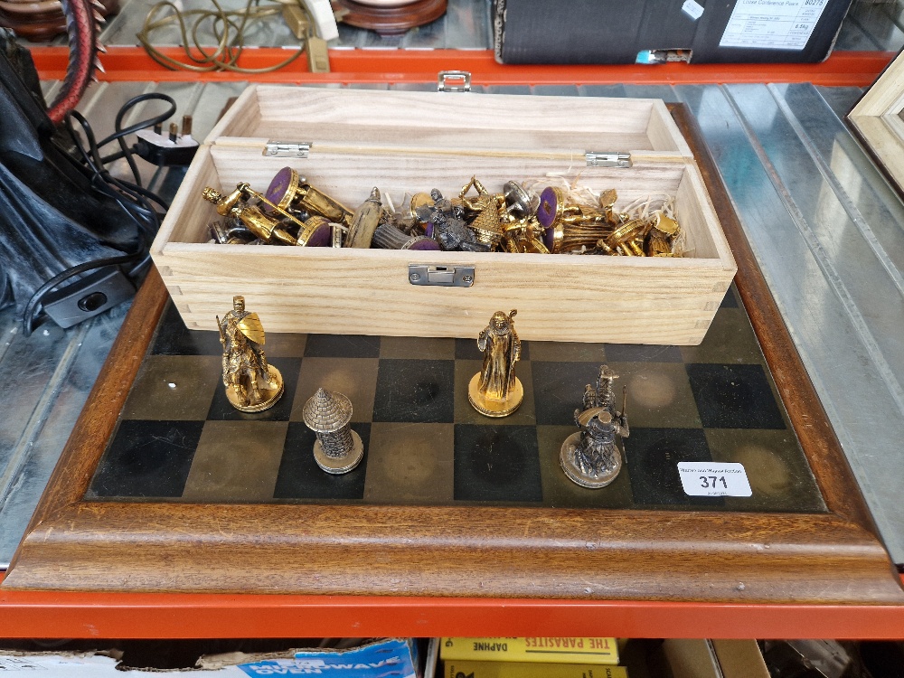 A cast metal chess set with wood framed copper plate board.