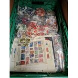 A crate of loose postage stamps and sheets of stamps