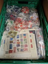 A crate of loose postage stamps and sheets of stamps