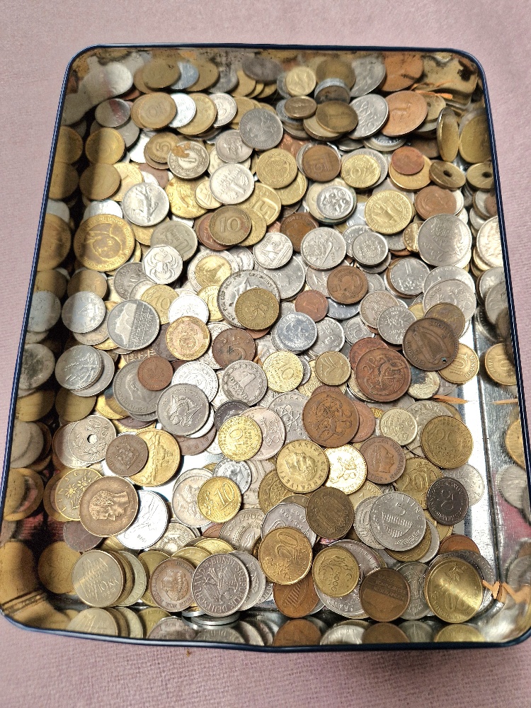 A vintage Harrods tin containing various world coins.