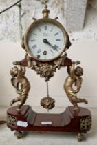 A brass mantle clock with cherubs by Rapport, London.