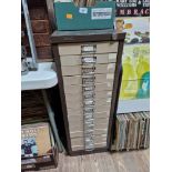 A 15 drawer triumph metal cabinet and contents comprising of clock making spares.