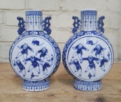 A pair of Chinese late 19th century blue and white porcelain moonflasks decorated with figures,