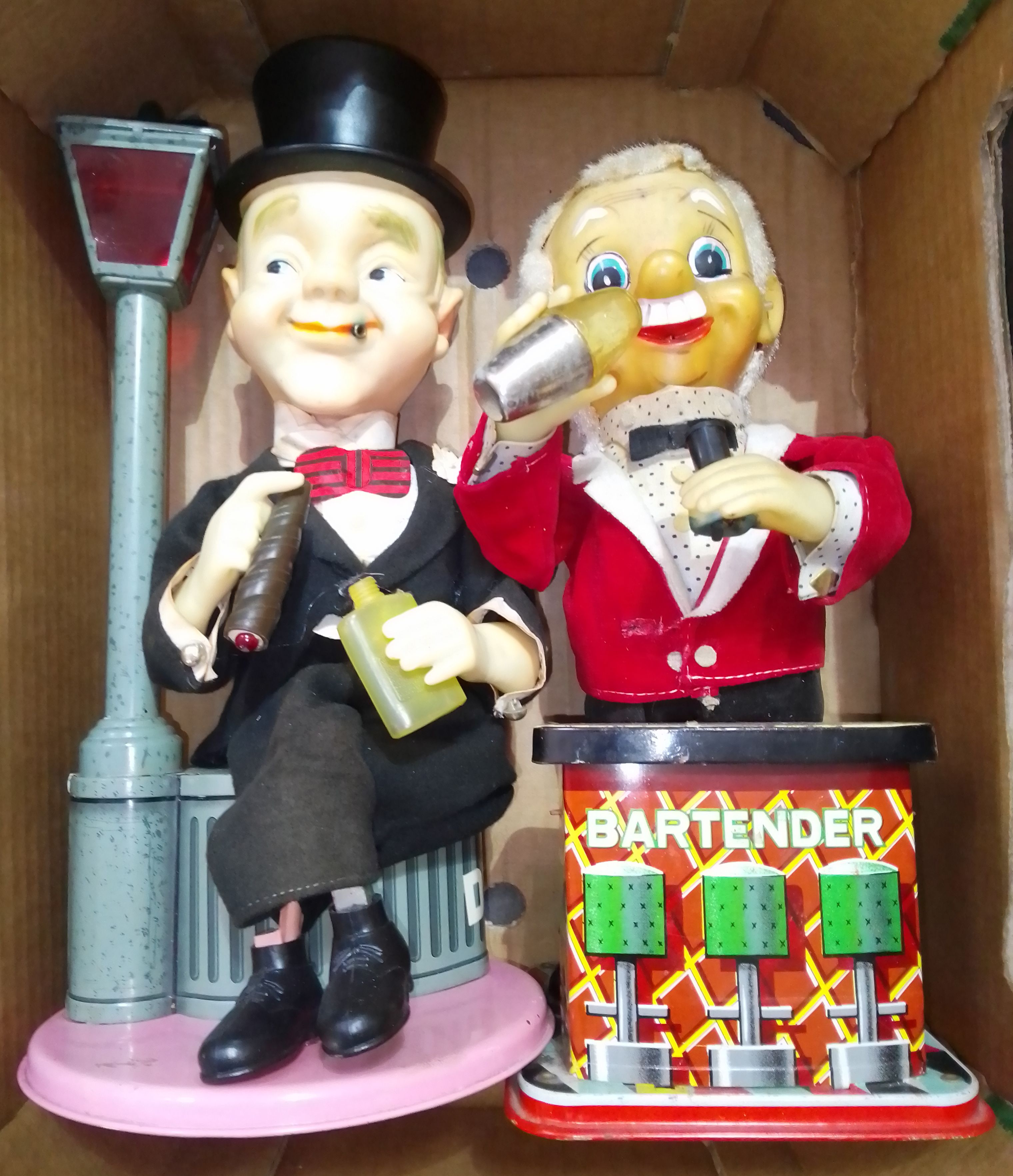 Two Japanese mechanical tinplate toys comprising of a seated man with cigar next to lampost & a