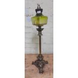 A cast brass oil lamp with green glass reservoir.