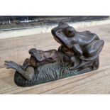 A 19th century cast iron mechanical money bank, modelled as a frog being fed by another, impressed