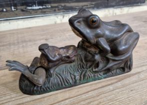 A 19th century cast iron mechanical money bank, modelled as a frog being fed by another, impressed