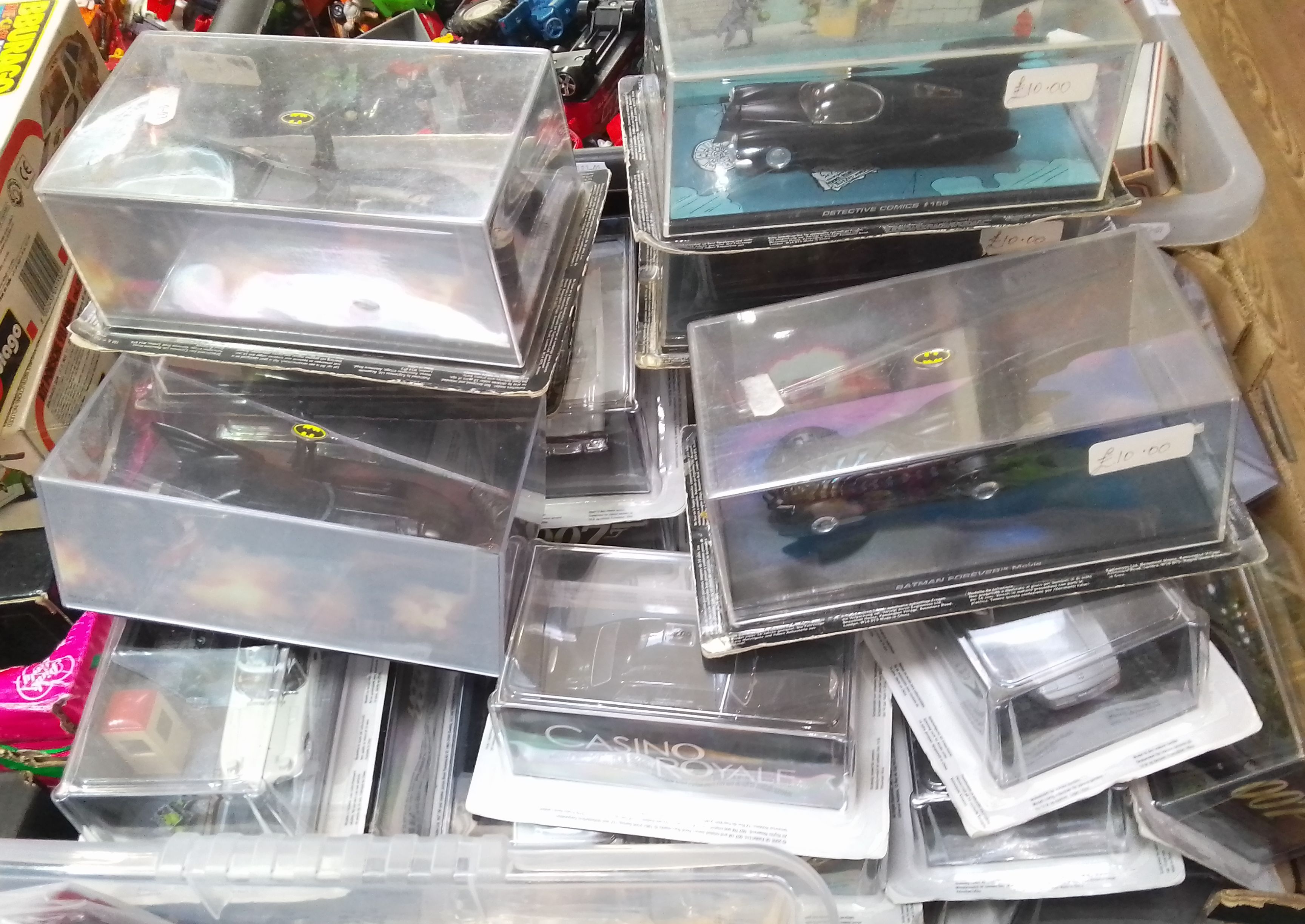 A box of James Bond 007 and Batman die-cast vehicles.