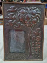 An Arts & Crafts copper picture frame decorated with birds, fruit tree and flowers.