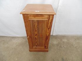 Pine pot cupboard with panelled door enclosing single shelf, standing on a plinth base - 14.5" x