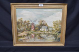 MK Buck, oil on canvas of windmill and buildings at a waters edge, in unglazed gilt frame - 17" x