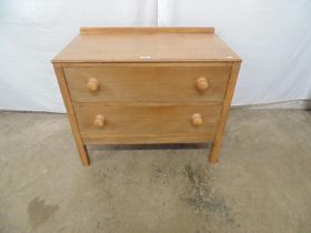 Low oak chest of two long drawers with knob handles under a raised back, standing on square legs,