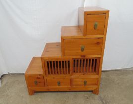 Hardwood stepped chest of drawers the drawers being opened either side with an arrangement of five