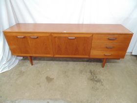 Mid century teak sideboard having a central fall front cupboard enclosing a fitted shelf flanked