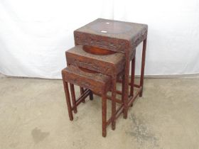 Nest of three carved Oriental style hardwood tables with figural decoration, standing on square