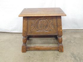20th century oak sewing box with lift top lid and carved front panel, standing on turned legs with