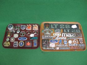 Two trays of metal and plastic vehicle manufacturers badges to include: Ford, Avenger, Golf GTI,