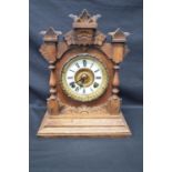 Oak cased mantle clock having some carving to case and standing on stepped base. Black hands and