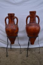 Pair of earthenware two handle urns on metal stands - 84cm and 79cm tall Please note descriptions