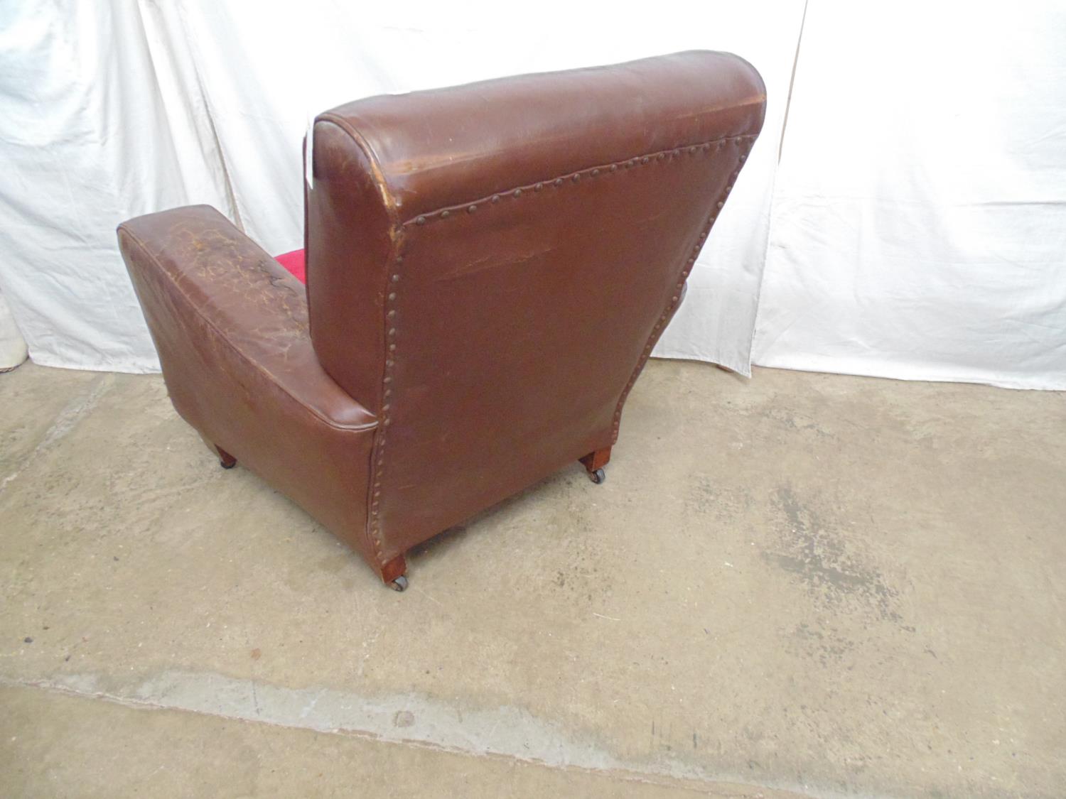 Brown leather club chair with red cushion, standing on block feet and castors (af) - 84cm x 72cm x - Image 5 of 5