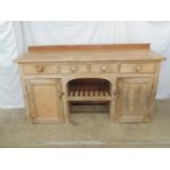 Victorian pine dresser base having raised back over four drawers with open arched centre, the