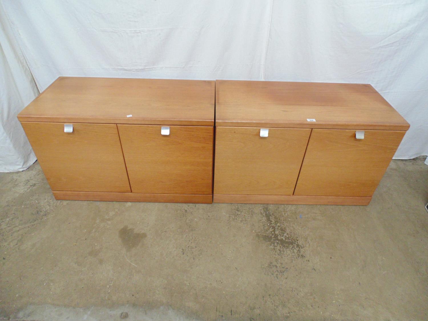 Pair of mid century teak cupboards the two door opening to a single fixed shelf, standing on