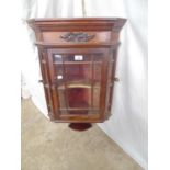 Mahogany corner wall cabinet with carved frieze over single glazed door opening to single shaped