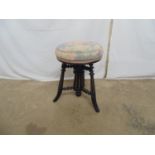Ebonised revolving piano stool having padded floral upholstered seat with out swept fluted legs -