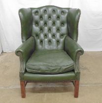 Green leather wing back armchair having button back and stud work detail, standing on square legs
