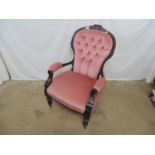 Victorian mahogany button back armchair having carved cresting rail and padded arms, standing on