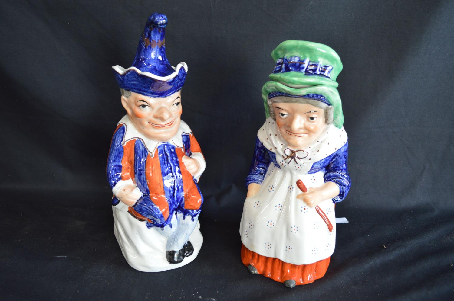 Pair of Staffordshire Toby jugs in the form of Punch and Judy complete with hat formed lids - 28cm