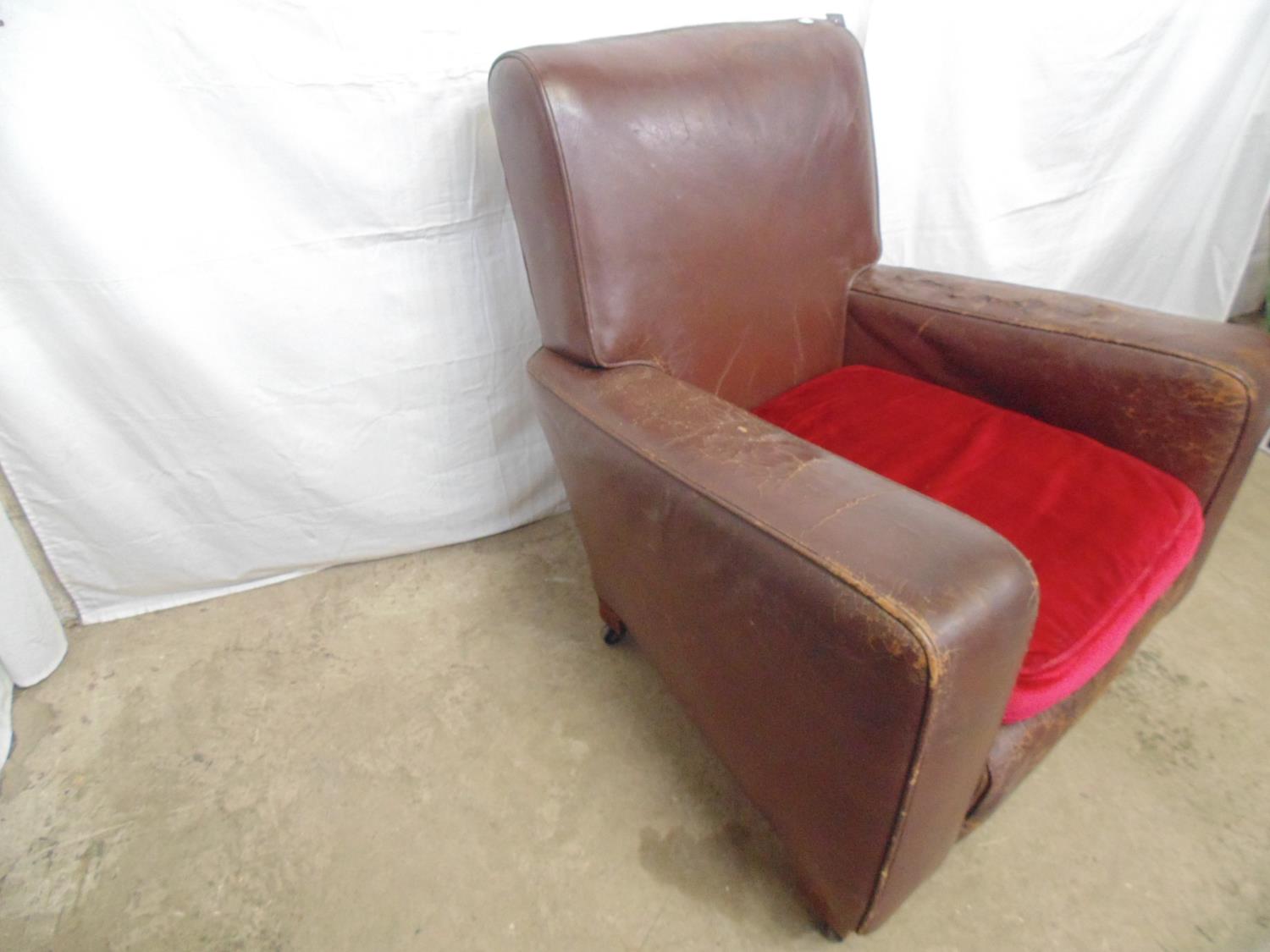 Brown leather club chair with red cushion, standing on block feet and castors (af) - 84cm x 72cm x - Image 3 of 5