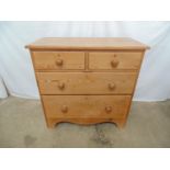 Pine chest of two short and two long graduated drawers with knob handles, standing on shaped apron