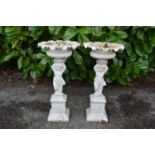 Pair of painted iron urns having gadrooned bowls supported by cherubs, standing on square bases -