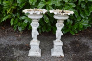 Pair of painted iron urns having gadrooned bowls supported by cherubs, standing on square bases -