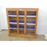 Light oak glazed bookcase having glazed central panel flanked by glazed doors opening to three fixed