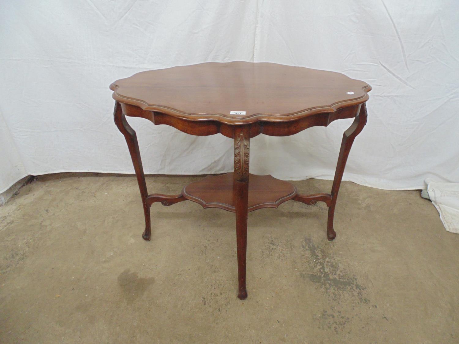 Mahogany two tier occasional table the shaped top over shaped frieze and carved shoulders leading to