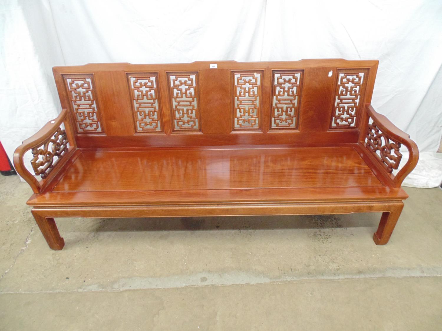 20th century Chinese hardwood bench having pierced back and arms, solid seat and standing on