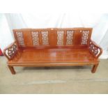 20th century Chinese hardwood bench having pierced back and arms, solid seat and standing on