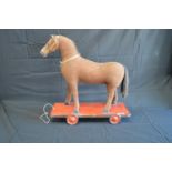 Vintage childs pull-a-long horse with wooden hoofs and mouth, standing on painted wooden base with