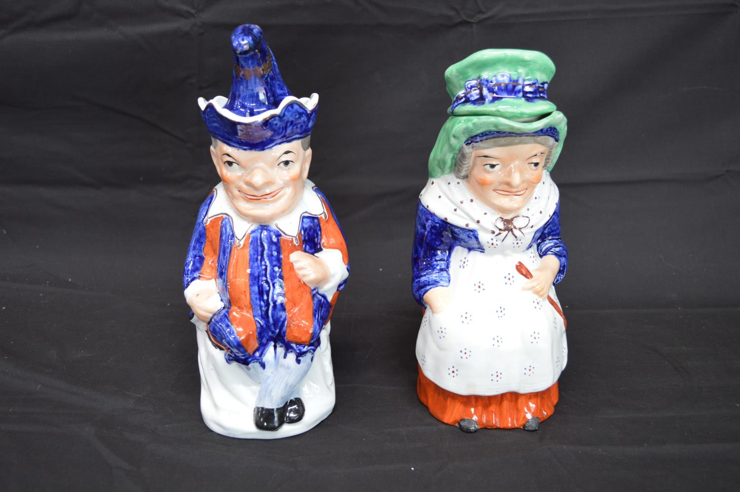 Pair of Staffordshire Toby jugs in the form of Punch and Judy complete with hat formed lids - 28cm