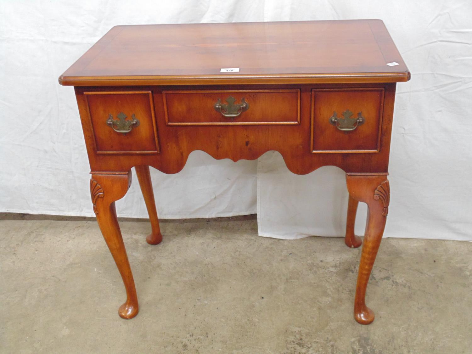 Yewwood lowboy having an arrangement of three drawers with swan neck handles, standing on four