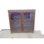 Aw-Lyn oak display cabinet the leaded glass doors opening to three adjustable shelves, standing on